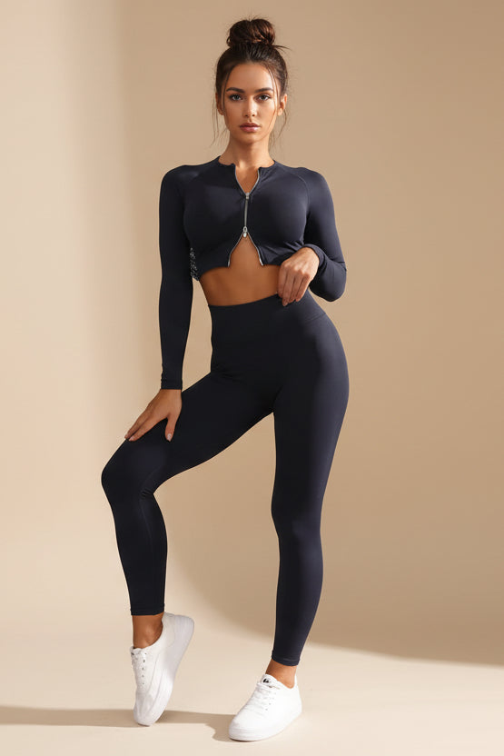 Woman wearing a black athletic outfit against a gray wall