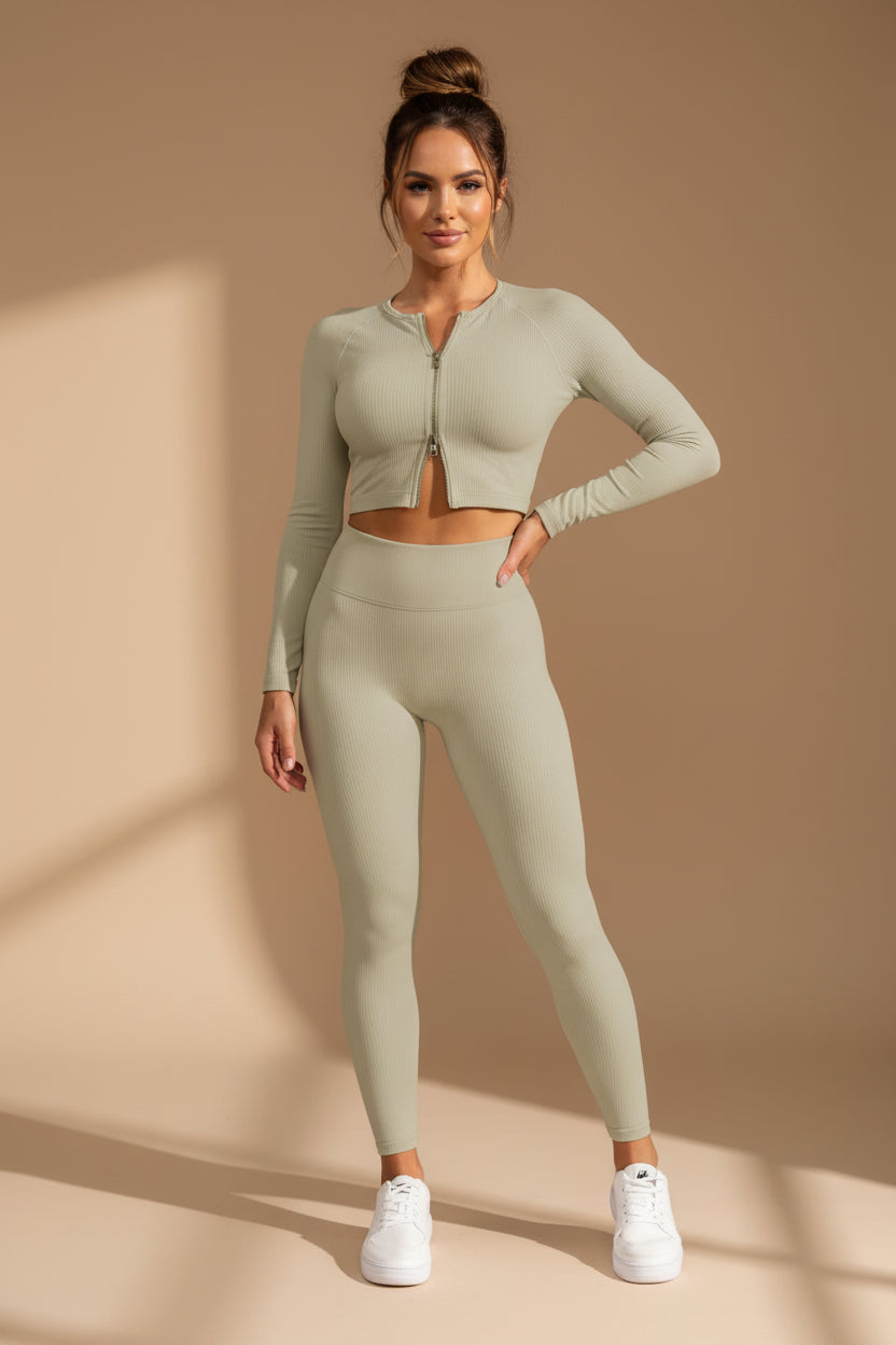 Woman wearing a light green athletic outfit standing against a gray wall.