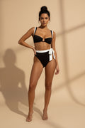 Woman wearing a black and white bikini against a white background