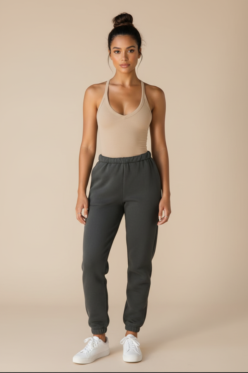 Woman wearing a beige tank top and gray sweatpants with a light gray cap on a white background
