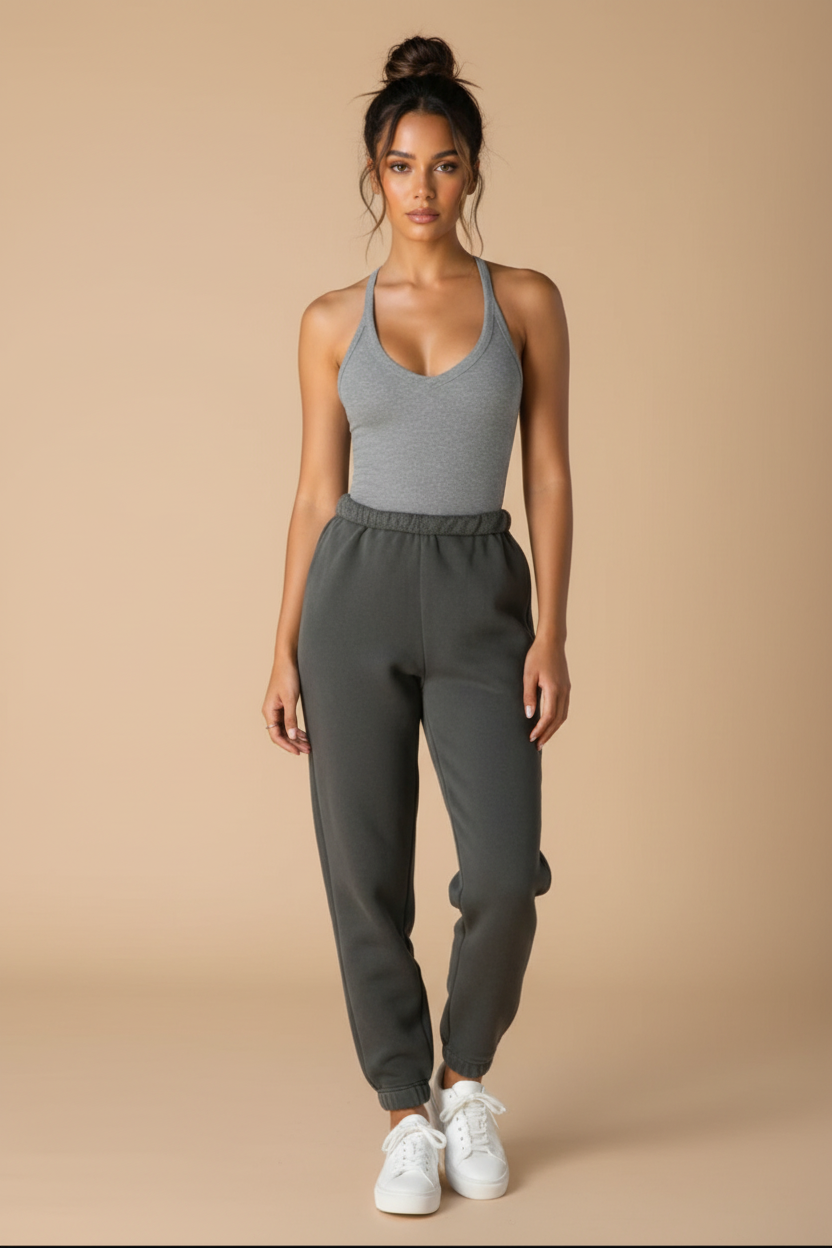 Woman wearing a gray tank top and sweatpants with a matching jacket on a plain background