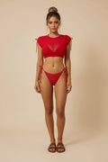 Red bikini set with tied sleeves on a plain background