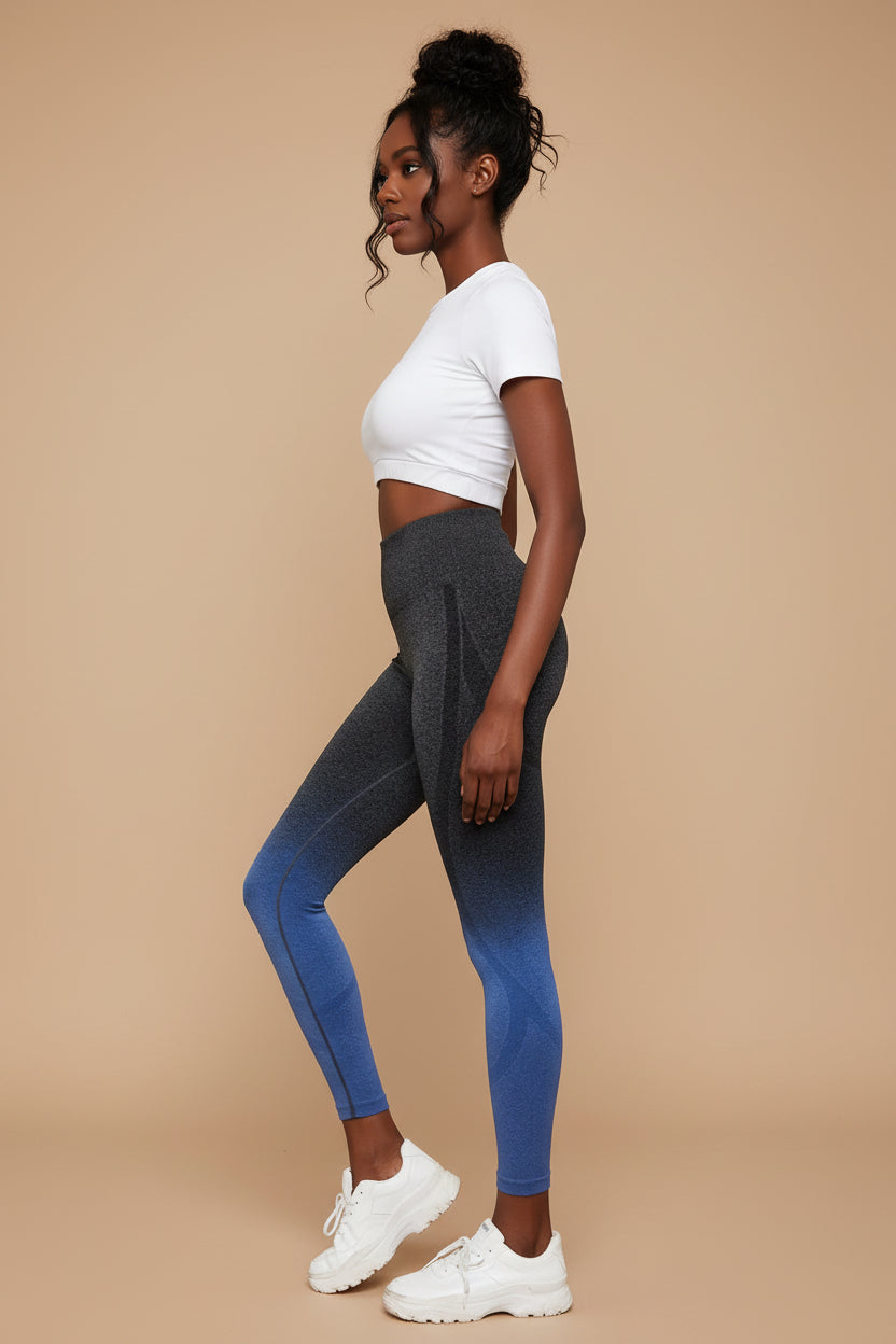 Person wearing gradient leggings with gray to blue color transition, white sneakers, and a blue wristband.